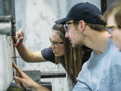 two students examining crack in concrete beam in lab