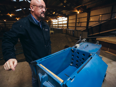 MMEC employee standing by custom-made machine that sample wool