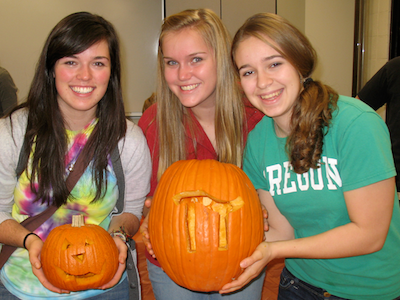 women students holding carved pumpkins at the Candyfest