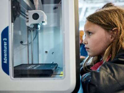 Photo of young girl watching a 3D printer